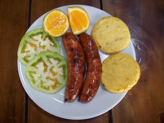 Chorizos (Bratwurst) - eine der leckersten gibts in Santa Rosa, wie im Foto typisch serviert mit Limone, Arepa & Tomatenscheiben  