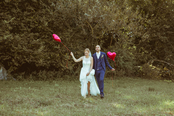 Hochzeitsbild von Julia und Clemens auf einer Wiese in Malterdingen mit Herzluftballons von Timo Erlenwein Fotografie