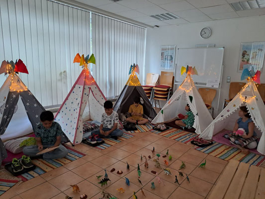 Die Kinder sitzen jeder in einem Tipi