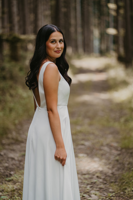 Braut im Brautkleid mit seitlichem Blick am Waldweg im Schwarzwald