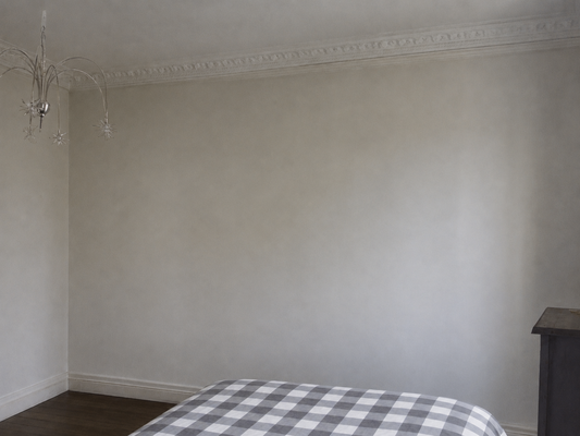 Chambre avant rénovation, aux murs blancs, avec cheminée et sans rangement, dans un appartement familial du quartier Ornano à Paris 18e.