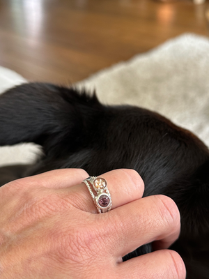 Ring gevuld met as, waarin de asdeeltjes zichtbaar zijn met een goud/beige glinstering. 