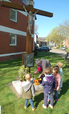 Kinder der KiTa St. Hedwig schmücken das Kreuz mit Tulpen.