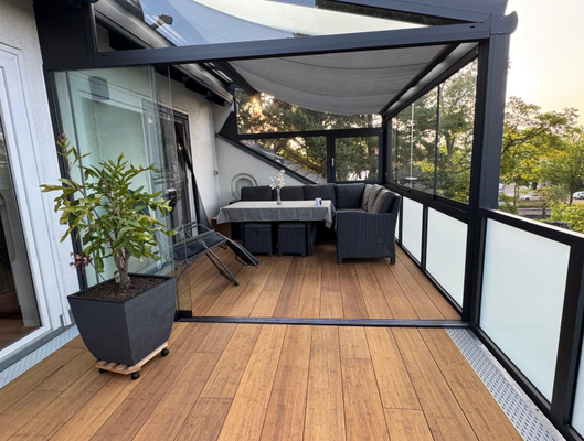 Die Bambusdiele Cristobal  unter moderner Überdachung an einem Einfamilienhaus, ausgestattet mit Gartenmöbeln. Nachhaltige Bambusdielen mit natürlicher Holzoptik, ideal für stilvolle und wetterfeste Terrassengestaltung.