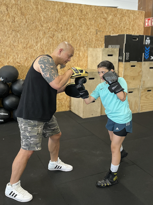 Kind beim Boxtraining mit Trainer im Kinderkampfsport Kurs im Fitnessstudio in Mainz