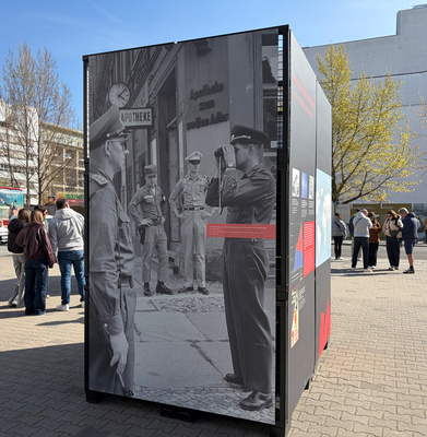 Das rückseitige Fotomit fast lebensgroßen US-Militärpolozisten und DDR-Grenzsoldaten an der Grenzlinie Friedrich- und Mauerstraße.