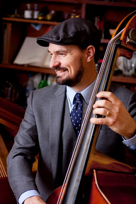 medium closeup of male upright bass player in suit, tie and swing cap (Clay Schaub)