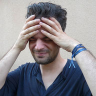 Mann fasst sich an den Kopf. Schmerzen im Kiefergelenk und Migräne