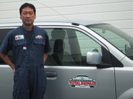 代表の小竹です。後ろに写っている車は初代営業車のeKワゴンです。