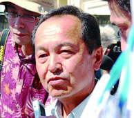 幹事会後に姿を見せた渡具知市議。取り囲む報道陣の質問には答えなかった=27日午後、名護市