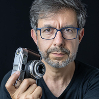 Photo du visage de Philippe Colin photographe, il est de face et tient un appareil photo vintage à la main droite, un Voigtländer  