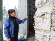 圧縮梱包された古紙を前に説明する現代表取締役社長の菊池さん。