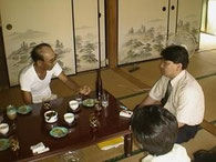 写真( H12・8)は、杜氏:宿里時吉(笠沙町)を訪ねて、焼酎造りを伺う若かりし頃の藤本一喜氏。