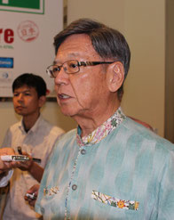 取材に応じる翁長知事。報道陣に怒りを表現してみせた=9日、那覇空港国際線ターミナルビル特別待合室前