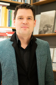 Porträt des Inhabers der Berliner Buchhandlung Knesebeck Elf vor einem Bücherregal
