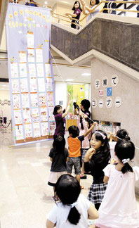 作った「100階建ての家」を吊り上げる子どもたち=5日午前、市立図書館
