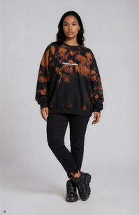 model wearing black distressed denim jeans with an black and orange acid-washed unisex sweater