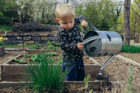 enfant qui arrose le jardin