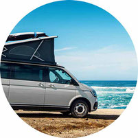 Camper Van in grau steht am Meer 2025