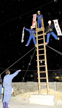 先輩団員の指導で、懸垂幕を掲示する(右から)三輪千夏さん、登野盛雅美さん、生駒さつきさん=7日午後8時半過ぎ、市消防本部