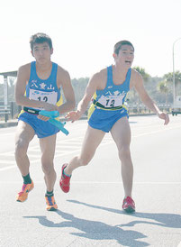 三ツ岩森之選手からタスキを受け取る島袋太佑選手=24日、宜野座村(第9中継所)