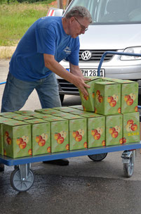 Ein Mann im NABU Tshirt stapelt Boxen voller Apfelsaft auf einen Wagen.