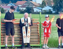 Ruhestandspfarrer Raimund Arnold mit den Ministranten segnet das Johannifeuer.