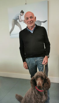 Photo de Philippe DUVAL debout tenant en laisse un caniche royal assis devant lui