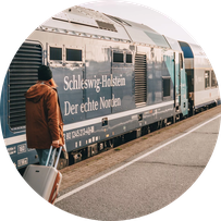 Ein Gast mit Koffer geht am Bahnsteig in Westerland auf Sylt zum Zug. 