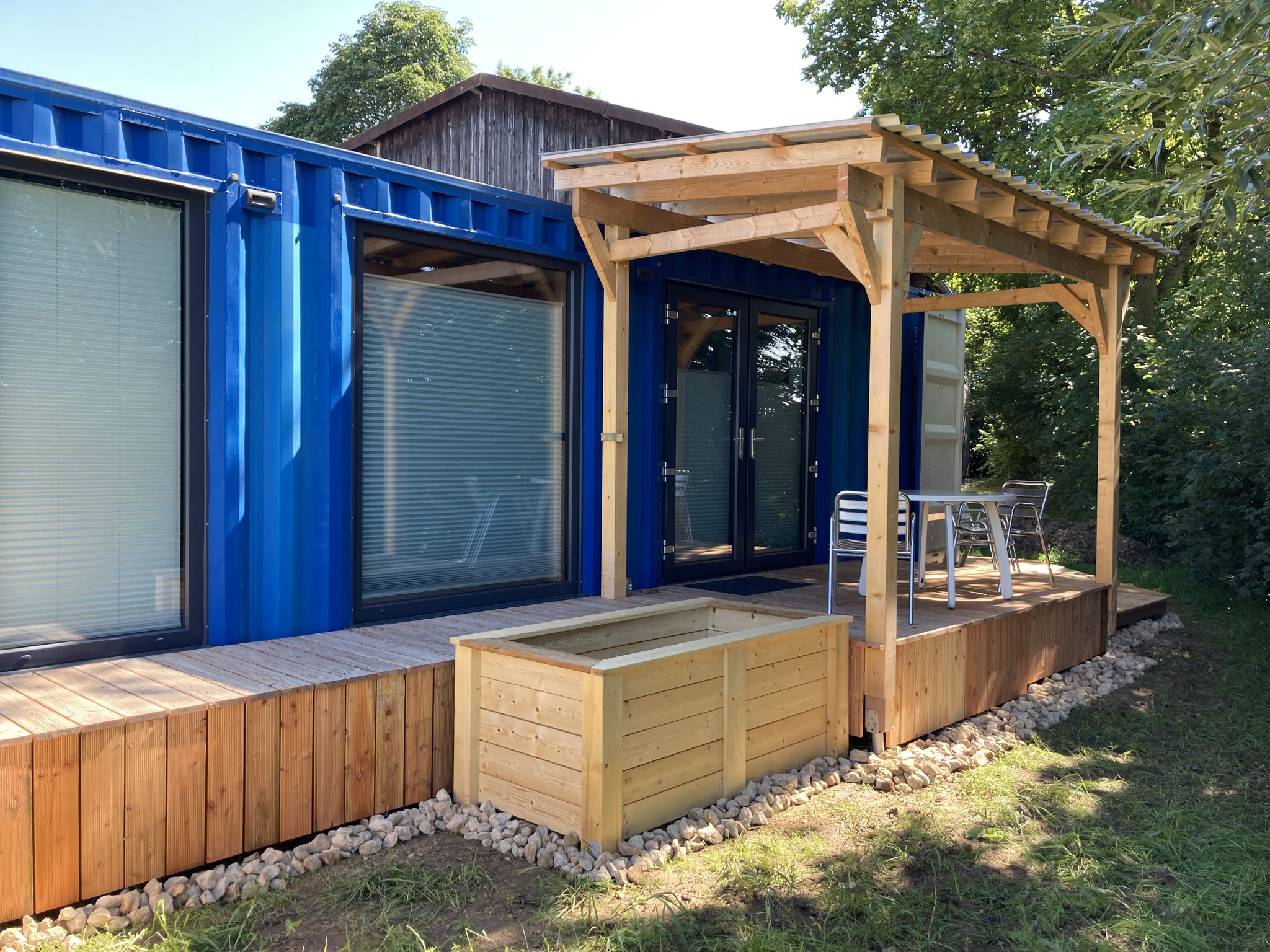 Holz-Veranda und Hochbeete vor Container-House