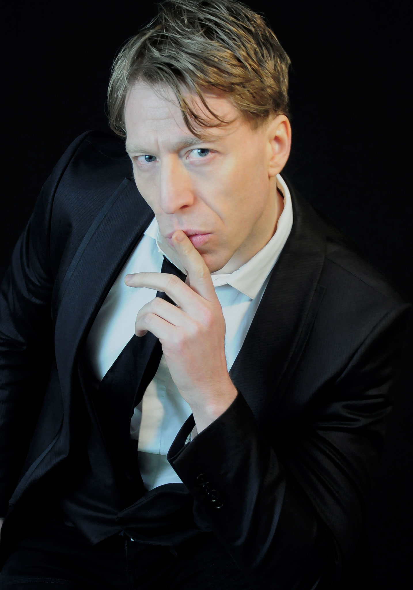 Ottaviano Blitch, actor and performer, pensive cinematic portrait with hand to chin against a dark background, attore performer ritratto cinematografico