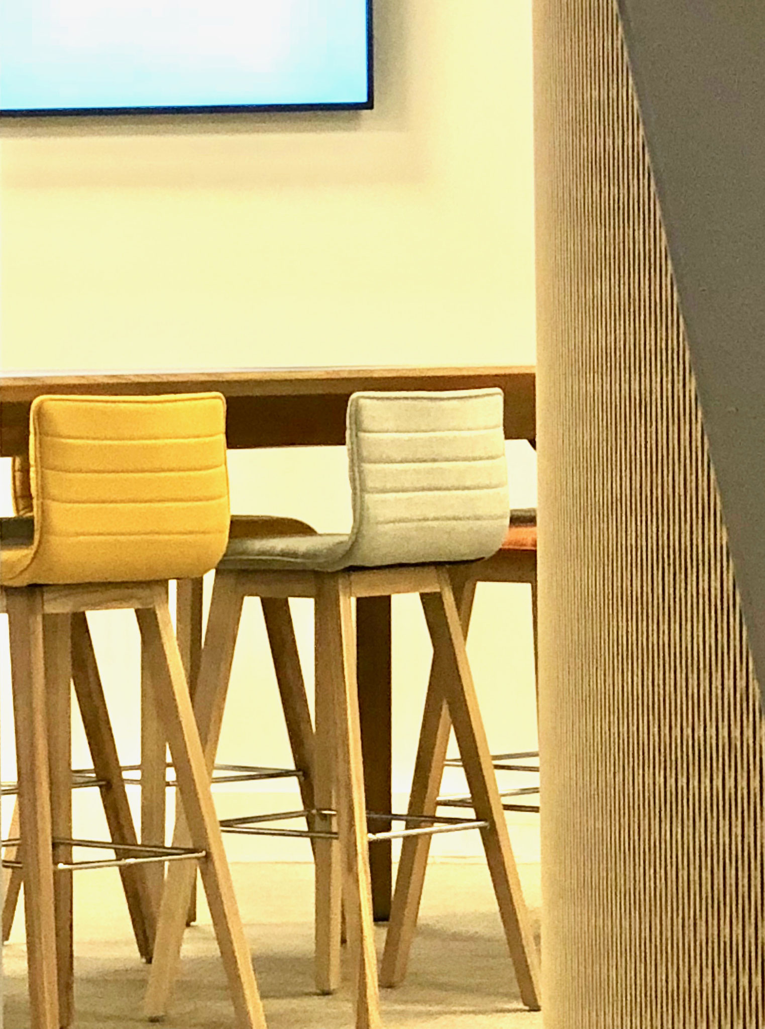 Une table haute pour des réunions, assortie de chaises hautes en flanelle pour le confort des collaborateurs.