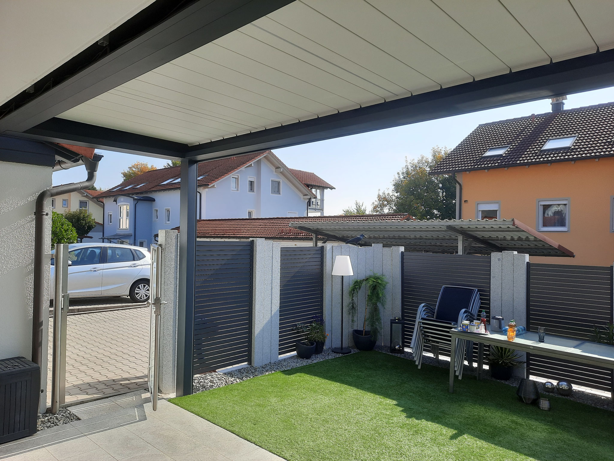 Terrassenüberdachung in anthrazit mit weißen Lamellen in kleinem Garten in München