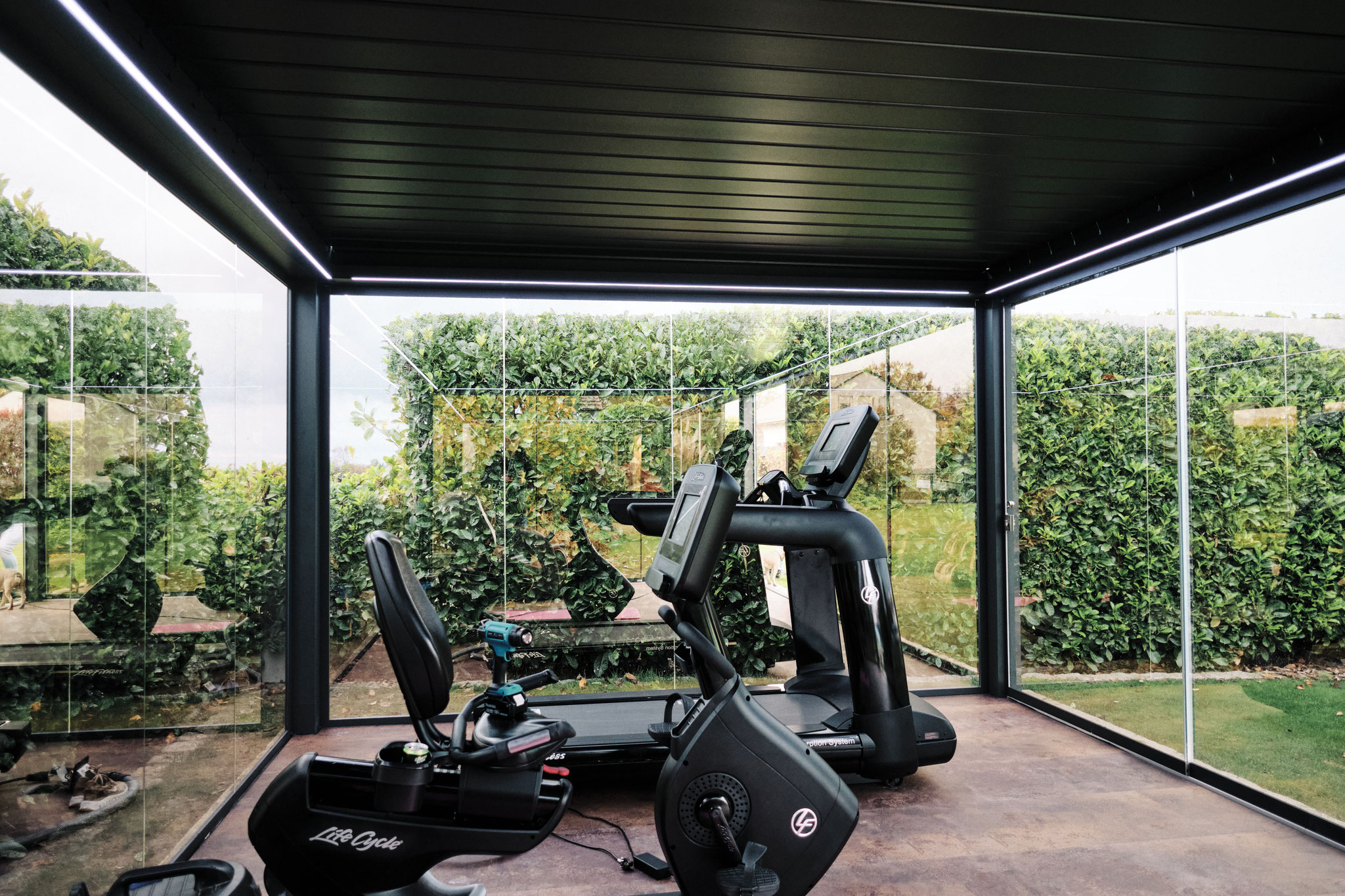 Terrassenüberdachung mit Lamellen genutzt als Fitnessbereich im Garten, ganzjährig nutzbar mit Terrassenheizung