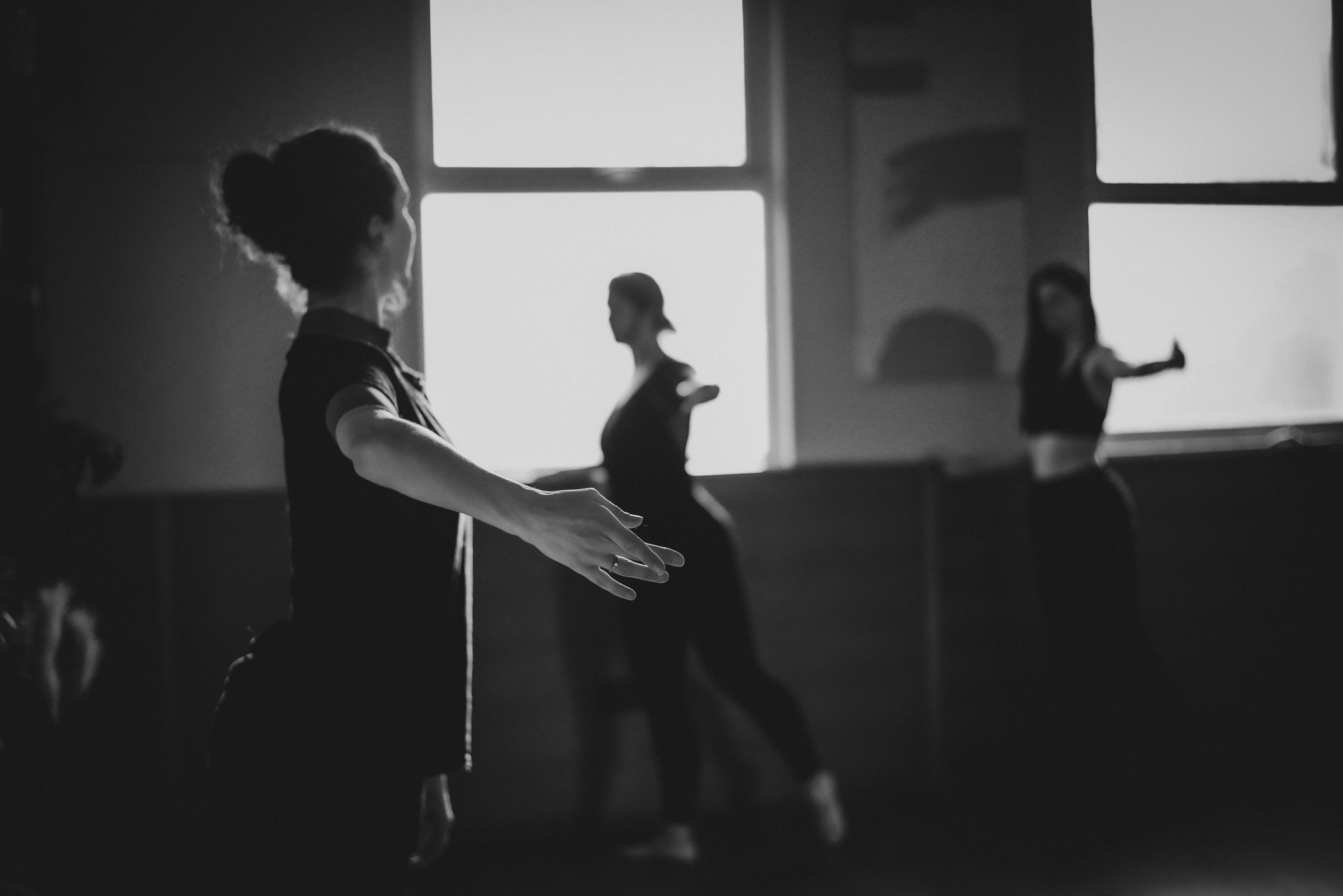 Black and white image of ballet coach dancing with adult students during class