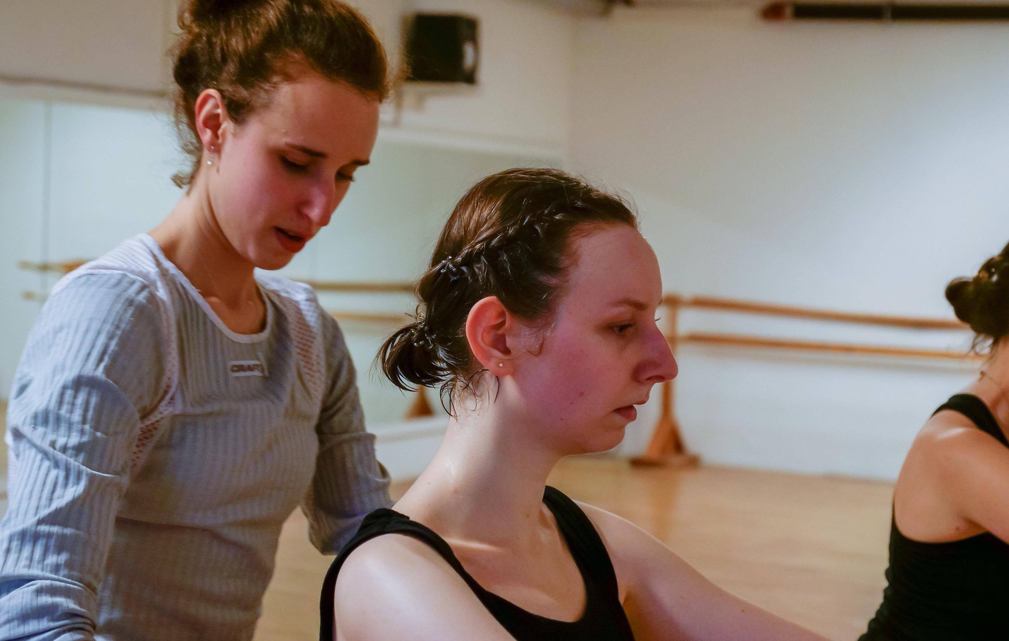 Ballet coach adjusting student posture during technique-focused lesson