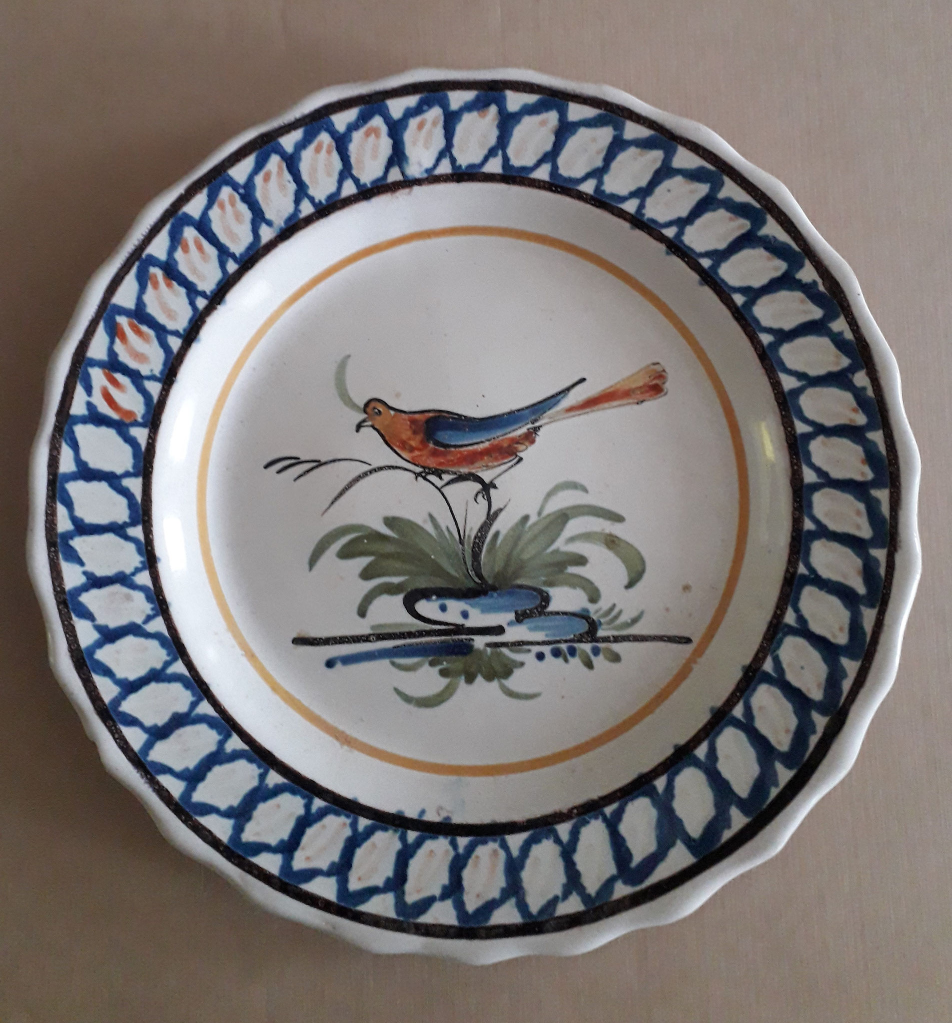 Assiette - Diam. 23 : assiette dentelée à 27 pointes. L'aile décorée à l'éponge et la représentation de l'oiseau au centre sont caractéristiques. Le plus souvent sur cette forme on trouve des décors floraux mais aussi des oiseaux, des paysages.