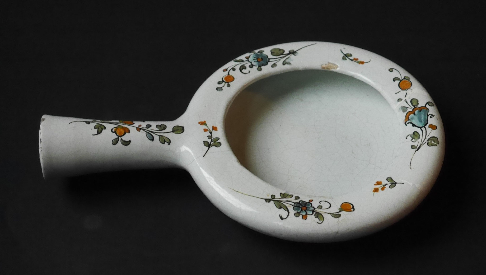 Crachoir - Long. 24.5 Diam. 16 : l'extrémité du manche (creux pour permettre la vidange) est simplifiée. Le décor floral découle des décors floraux du 18ème siècle mais la qualité est moindre.
