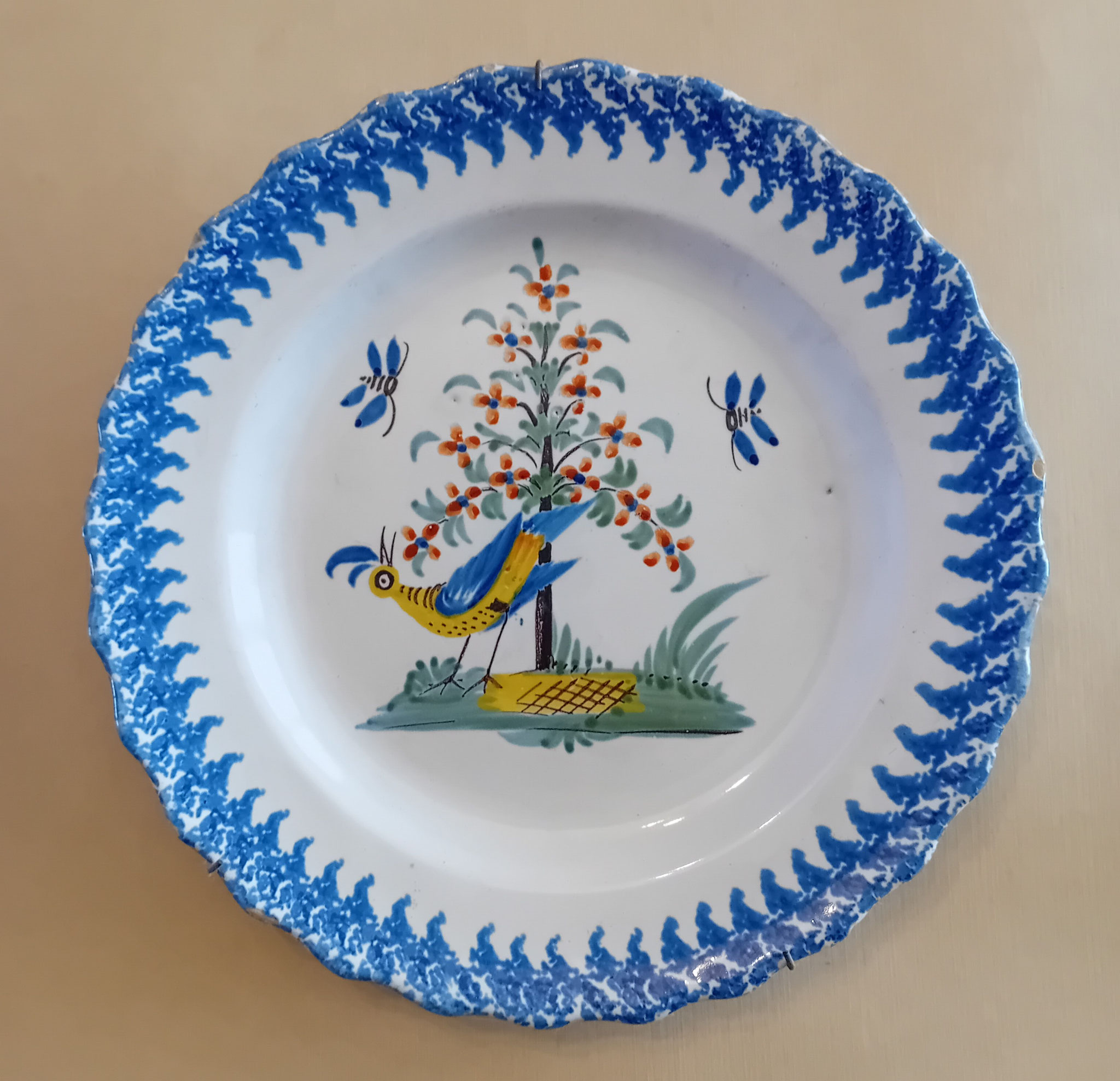 Assiette - Diam 23 : assiette dentelée avec un décor central de l'oiseau et d'insectes sur un tertre arboré dont l'aile.