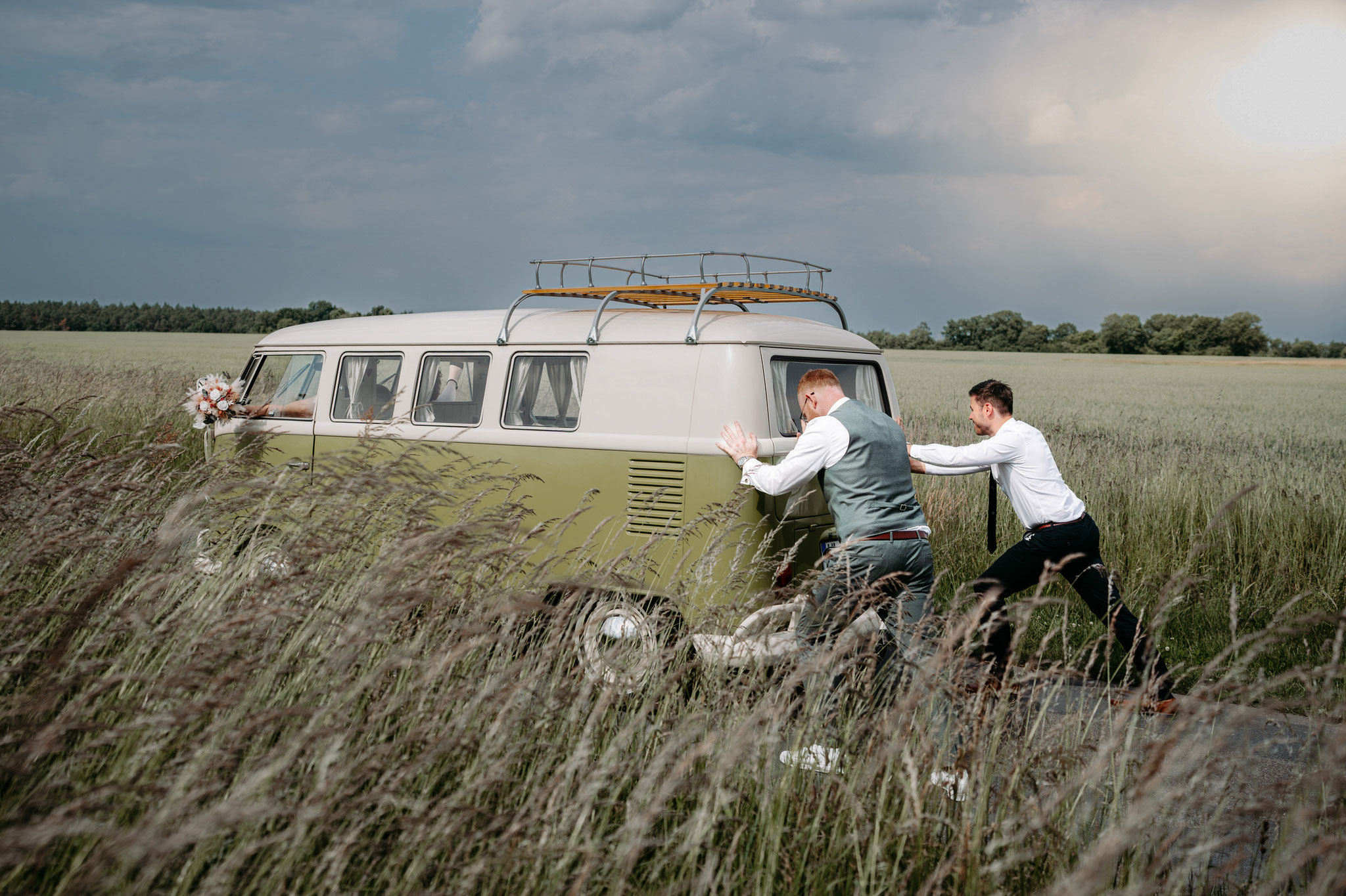 Bräutigam mit Trauzeugen schiebt das Hochzeitsauto nach einer Autopanne in der Lüneburger Heide