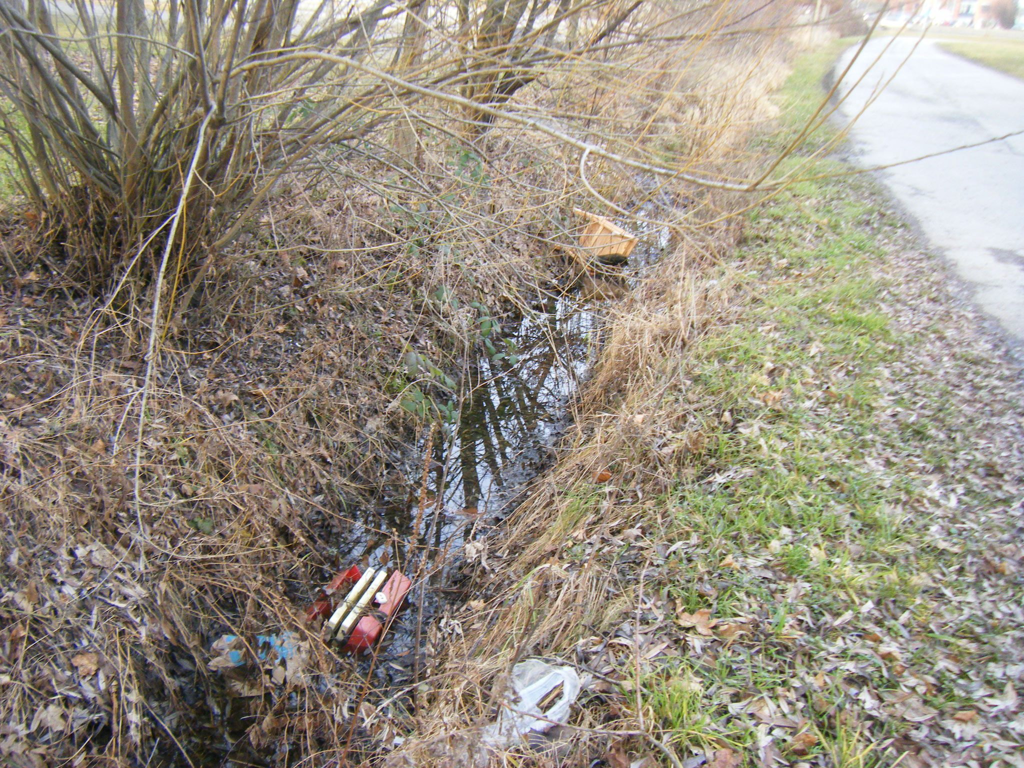 im Abwassergraben auf dem P7-Parkplatz: Sperrmüll, ein Stuhl und ein Plastik-Werkzeugkoffer