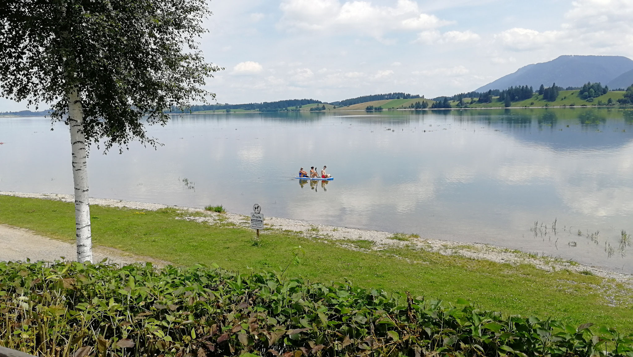 Drei Mann/Frau auf einem SUP