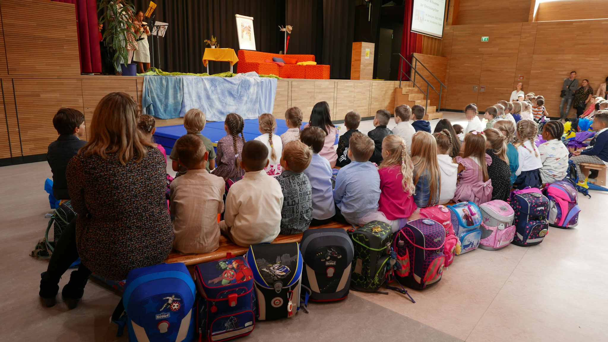 Frau Pawlak und ihre Klasse schauen den Flötenkindern zu