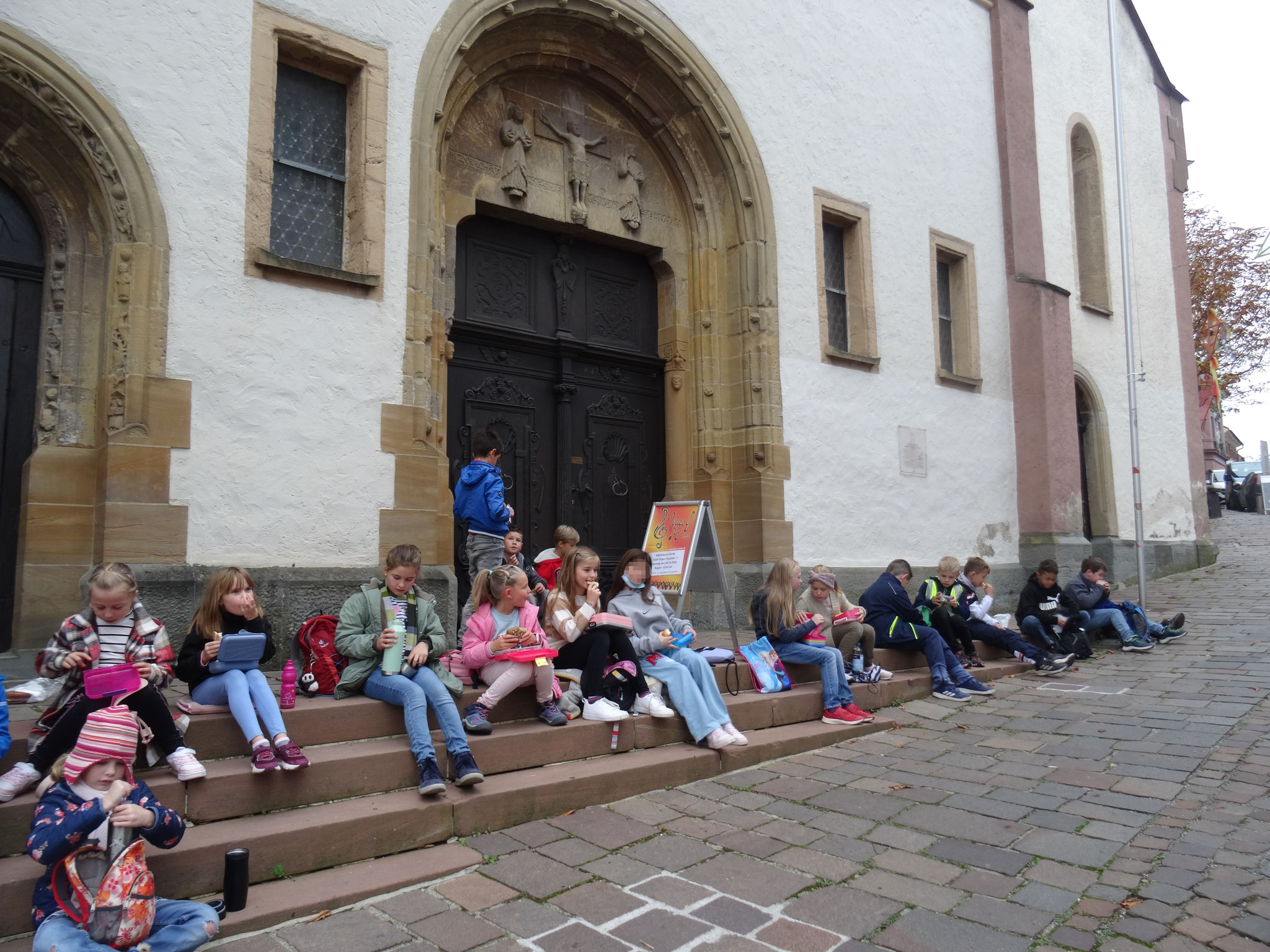 Kinder sitzen auf der Treppe vor der Kirche Mariä Himmelfahrt