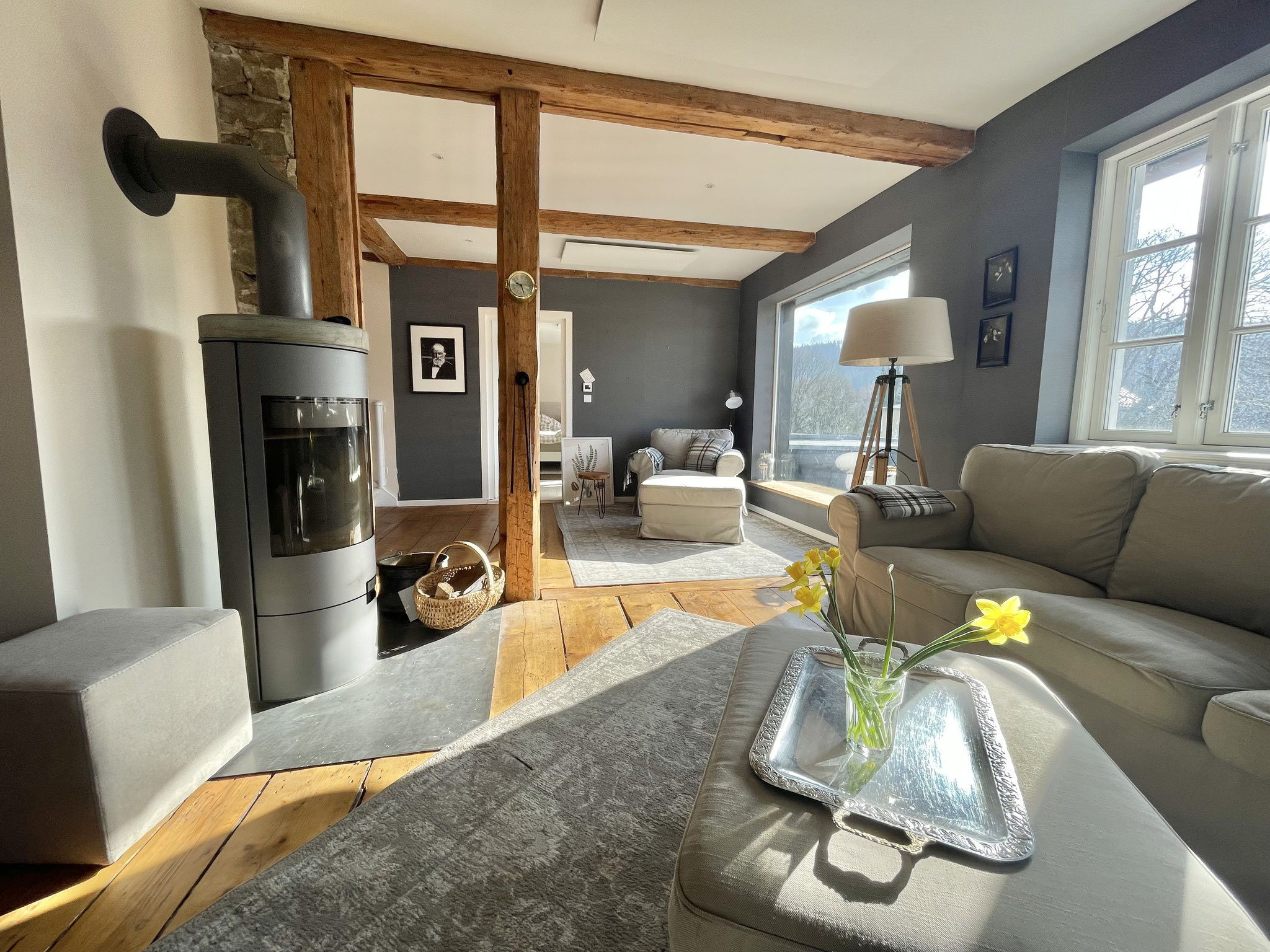 Im großzügigen Wohnzimmer mit Kaminofen und Panoramafenster ist Platz für alle. 