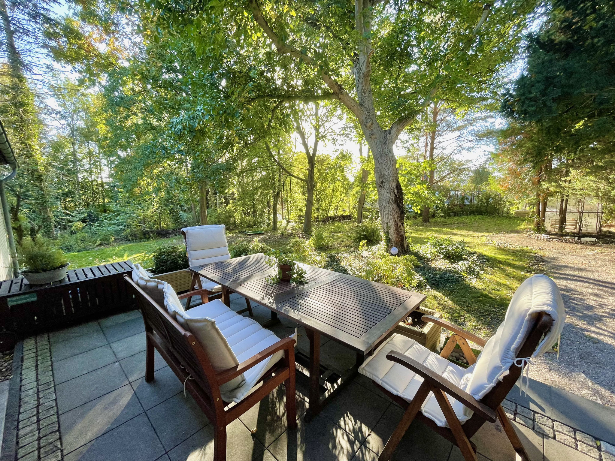 Die gemütliche Terrasse mit Blick in den Waldgarten ist ausgestattet mit Esstisch, Sonnenschirm und Grill.