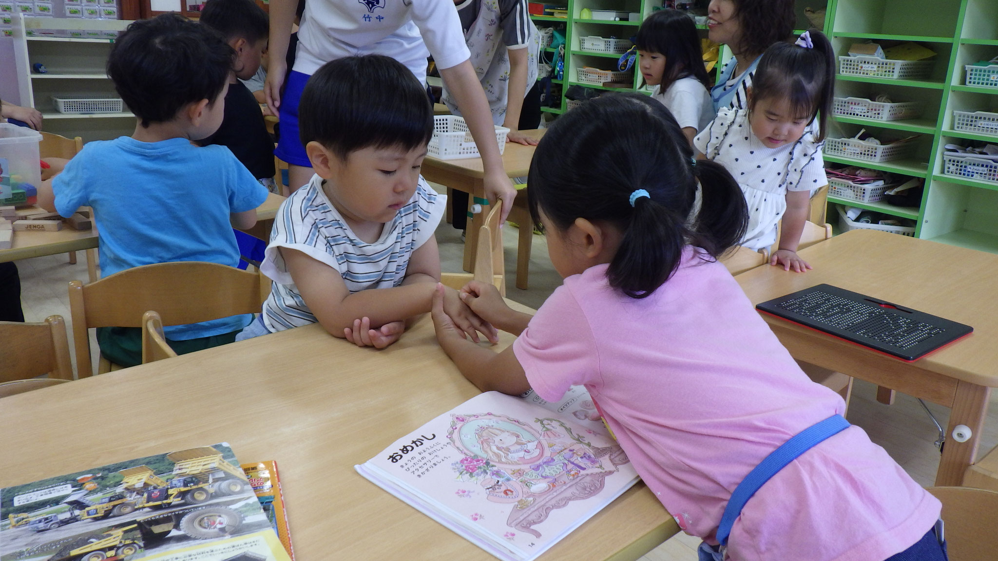 7月8日　お化粧の絵本を見ながら、友達にお化粧をしています。