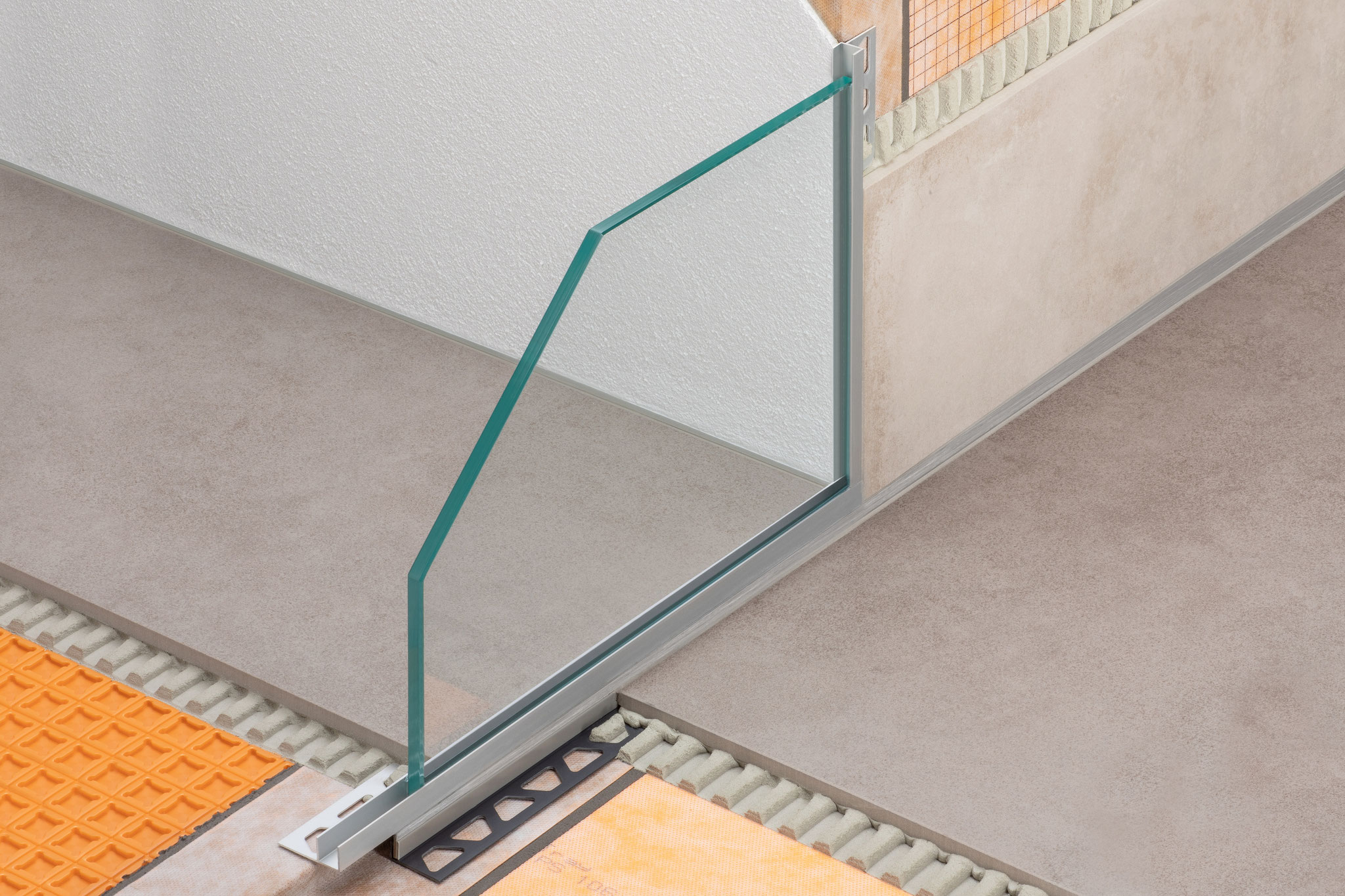 Schlüter-DECO-SGC nimmt Glastrennwände an Ecken von bodenebenen Duschen mit angrenzenden Putzwänden sicher auf.