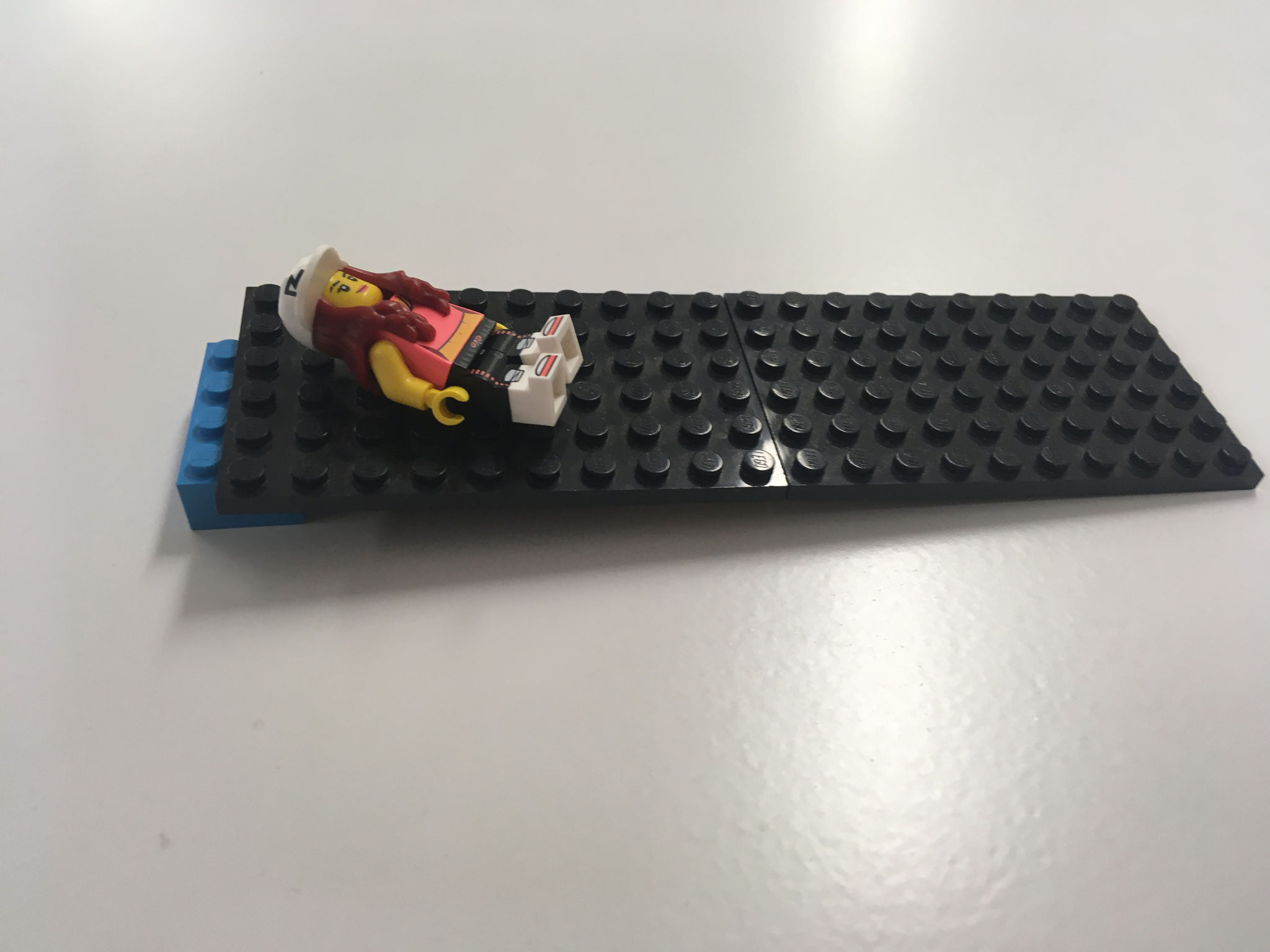 Lege ein Lego-Männchen auf eine Seite der Platte und lege dann …