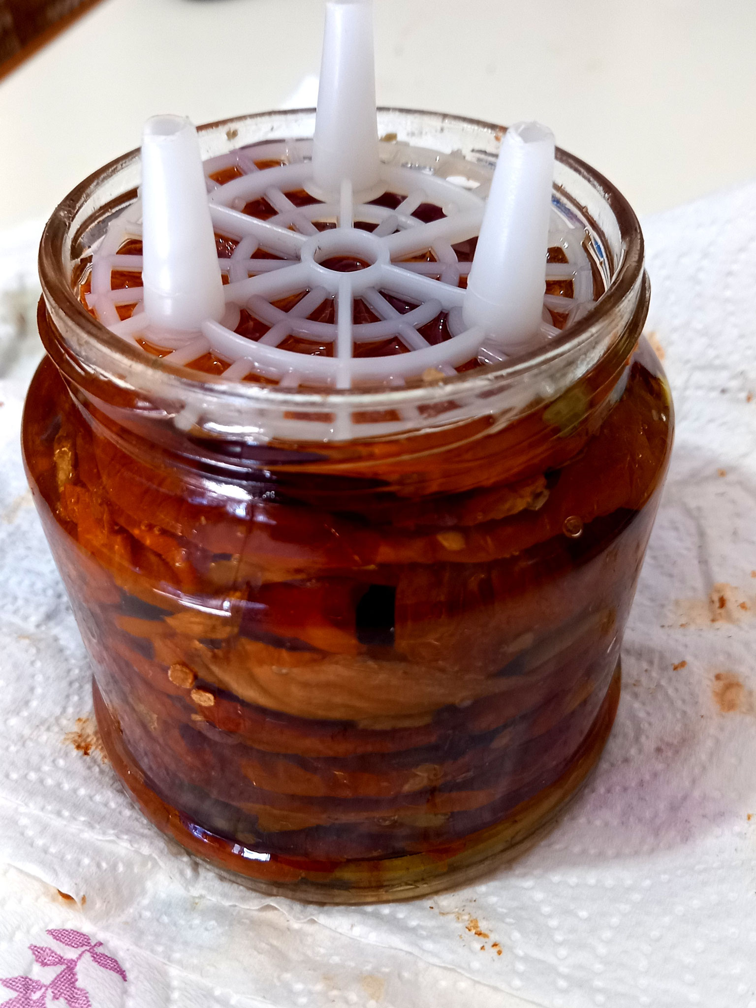 Inserire un pressore di plastica e completare il riempimento con olio fino a coprire l'ultimo strato di pomodori.
